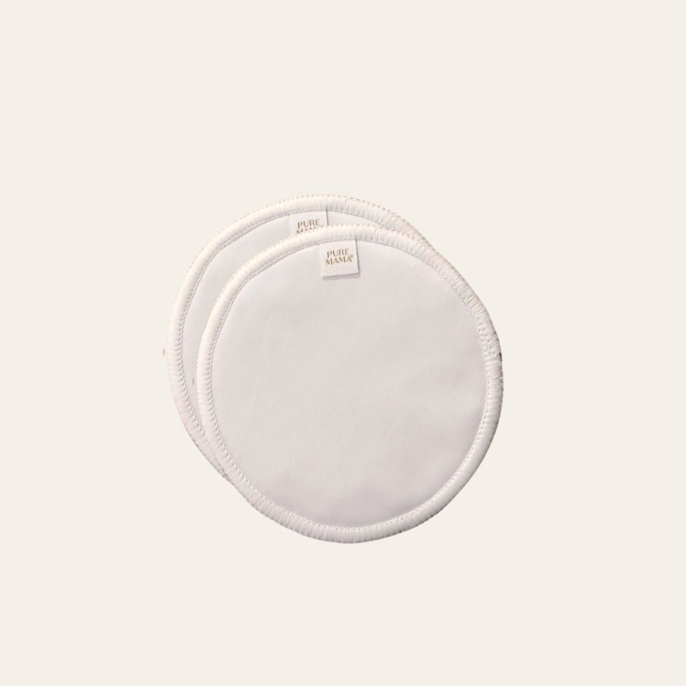 Two round, white Pure Mama Nursing Pads made of reusable bamboo overlap on a light background, each with stitched edges and a small fabric label near the edge.