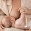 A mother breastfeeds her baby while holding a tube of Pure Mama NZ Nipple Butter. Text on the image notes that a clinical study showed the product boosts skin hydration by 46.5% in 14 days.