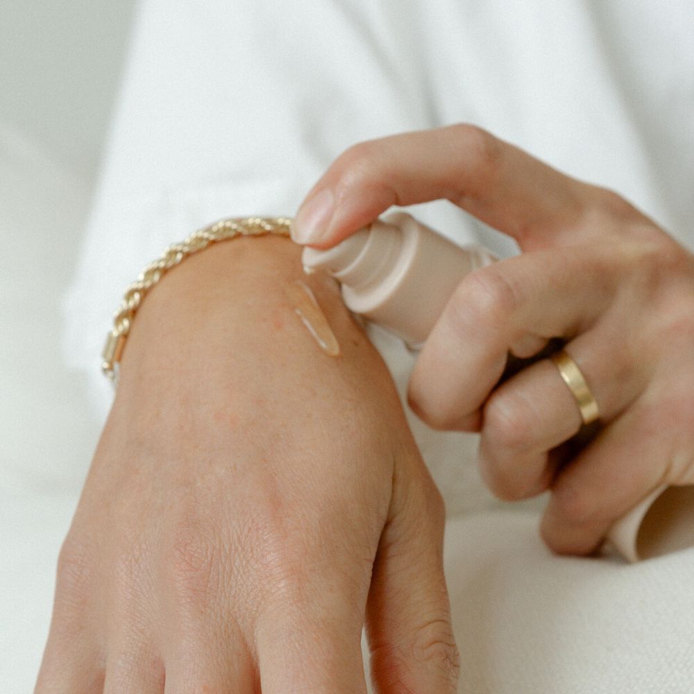 A person wearing a gold ring and bracelet pumps Pure Mama NZ Perineal Massage Oil onto the back of their hand. The oil is known to improve skin elasticity and help reduce tearing.