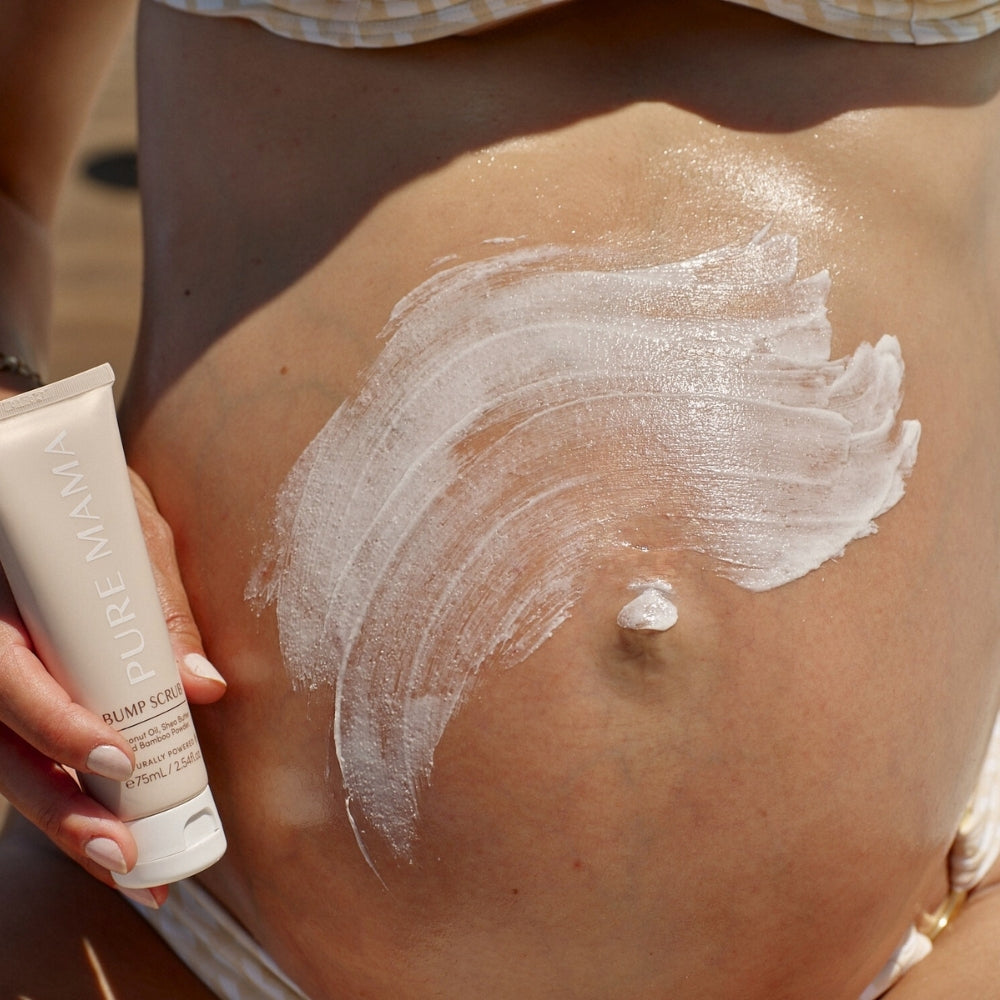 A person applies a thick layer of white lotion from the Pure Mama NZ Belly Spa Kit to their bare pregnant belly.