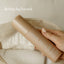 A hand holds a bottle of Pure Mama NZ Post Birth Relief Spray above an open bag with a towel inside. “Birthing Bag Essential” appears in the upper left corner.