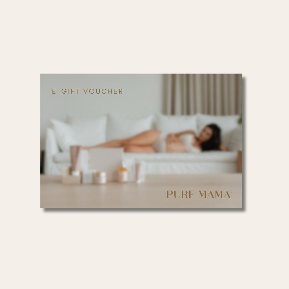 A blurred PURE MAMA Gift Voucher by Pure Mama NZ with gold text. In the background, a woman relaxes on a white sofa beside skincare products, creating a calm, minimal setting that highlights this elegant gift option.