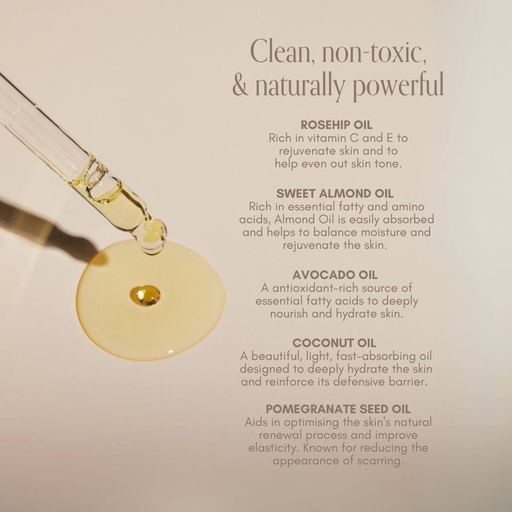 A glass dropper dispenses Pure Mama NZ Belly Oil Mini—a golden blend of rosehip, sweet almond, avocado, coconut, and pomegranate seed oils—onto a beige surface. This pregnancy skincare helps prevent stretch marks.