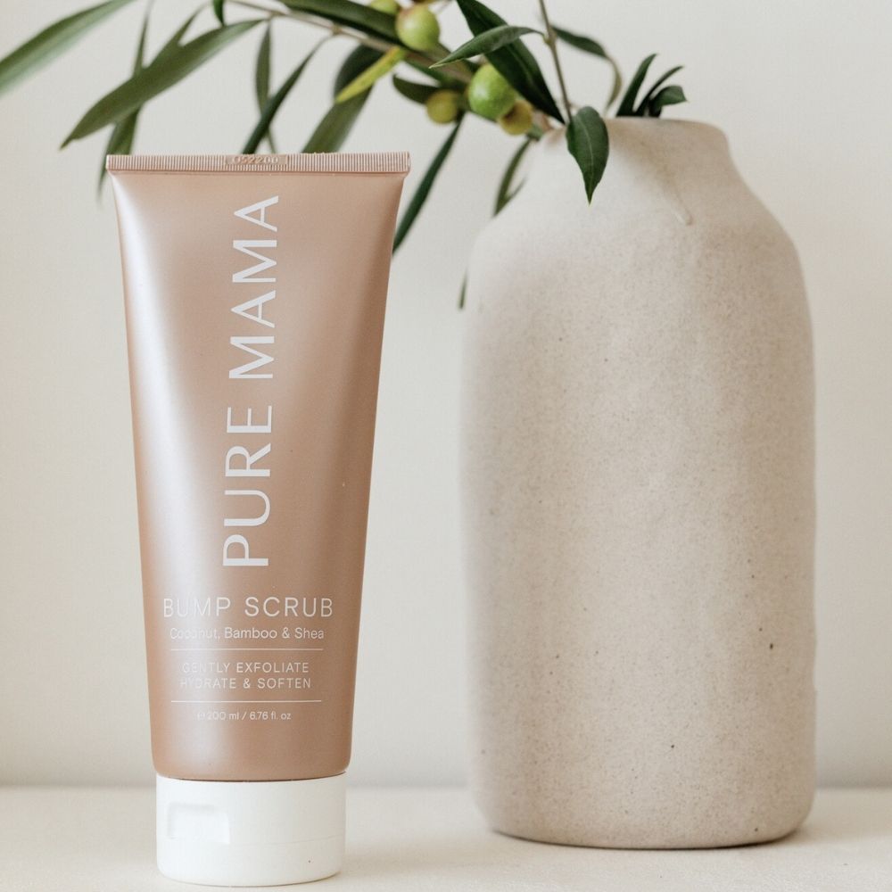 The Pure Mama NZ Pregnancy Care Set stands upright beside a beige ceramic vase with green leaves and olives on a light surface, creating a soft, natural pregnancy care aesthetic.